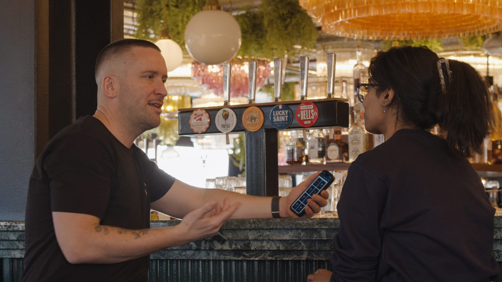 Froth Distribution Founder accessing Bowimi in pub in front of taps with Bowimi Customer Success