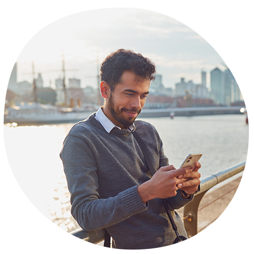 Man looking at mobile, sea and city backdrop